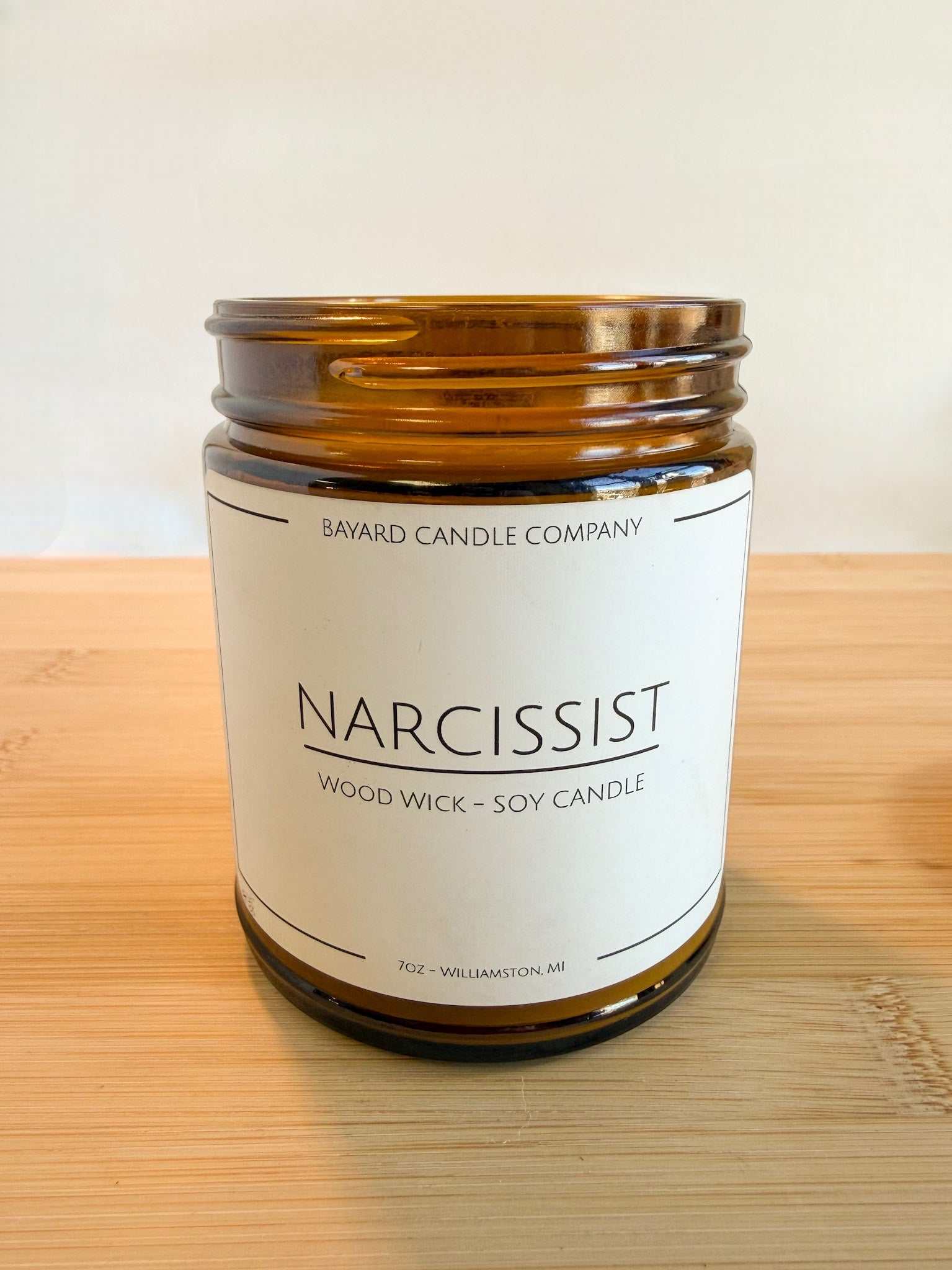 Narcissist wood wick soy candle with lid off showing natural soy wax and wood wick in amber jar