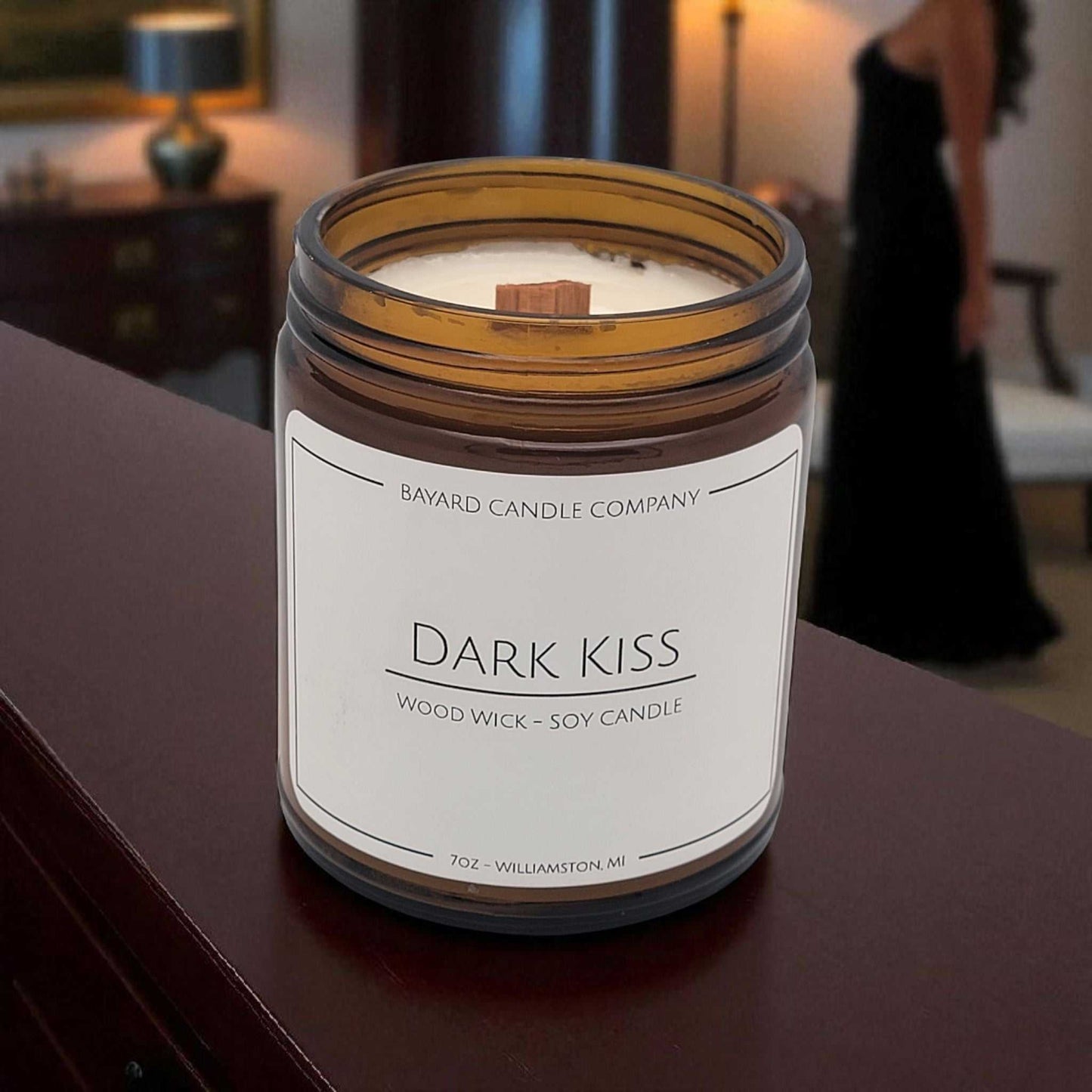 Dark Kiss Wood Wick Candle on a wood table in a bedroom