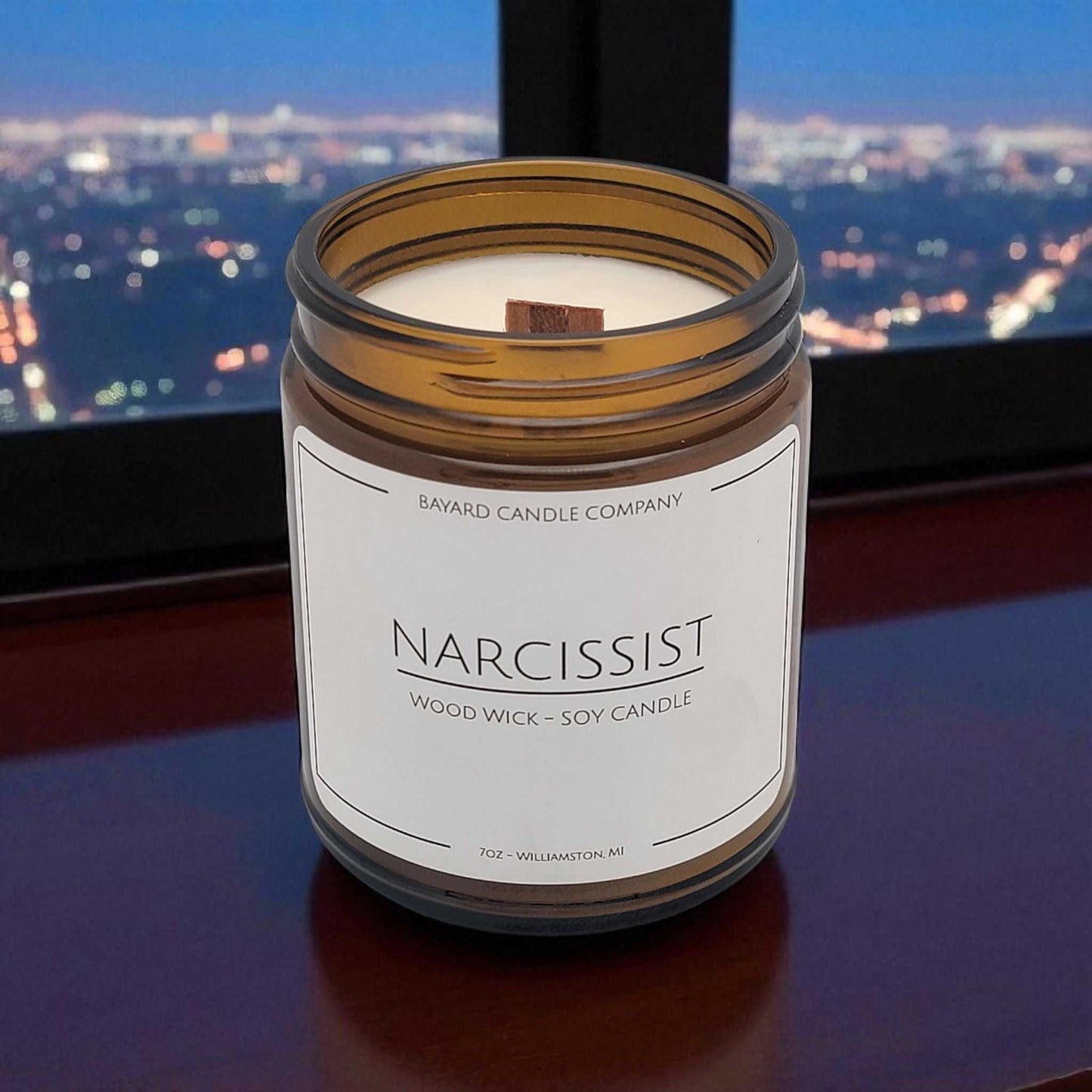 Narcissist Wood Wick Candle by a window overlooking Los Angeles at night