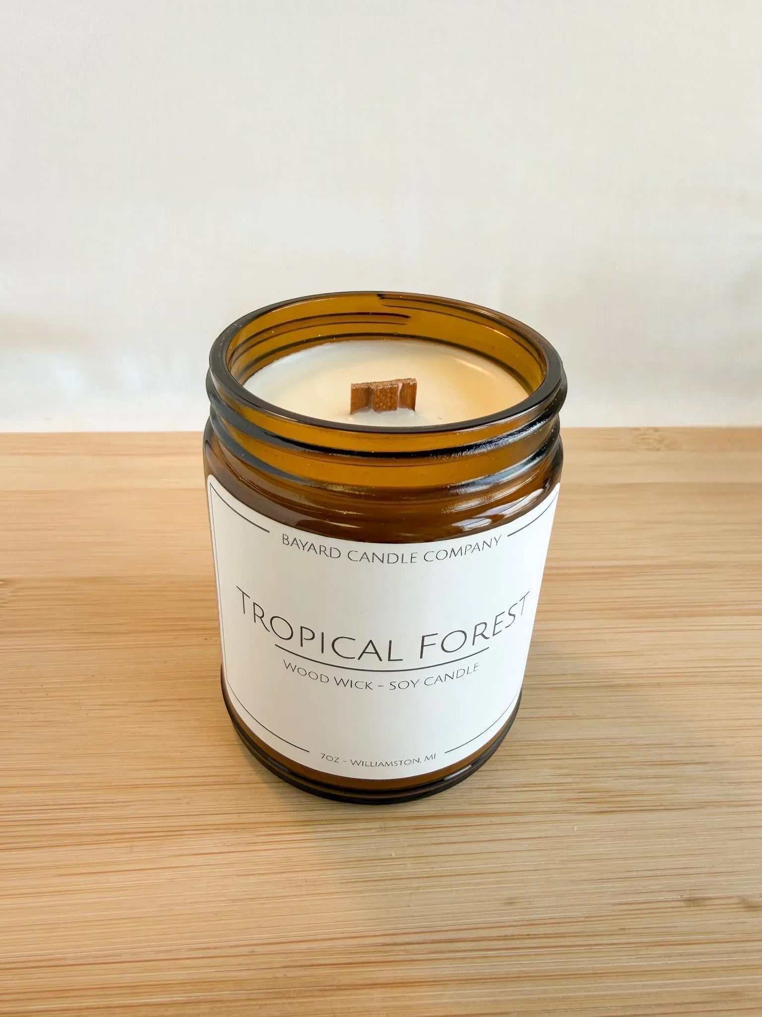 Tropical Forest wood wick soy candle in amber jar with lid off, showing natural soy wax and wood wick