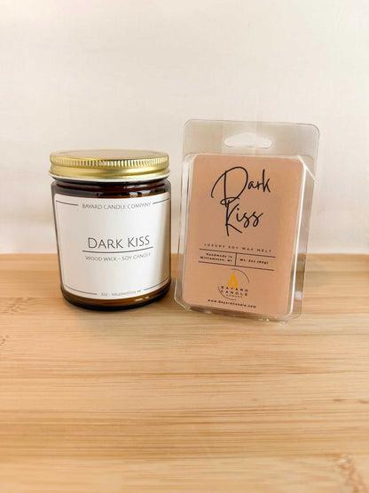 Dark Kiss wood wick soy candle with matching wax melt set, amber jar candle and scented melt on wood surface