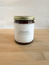 Dreams wood wick soy candle in amber glass jar with gold lid on wood surface, clean minimalist background