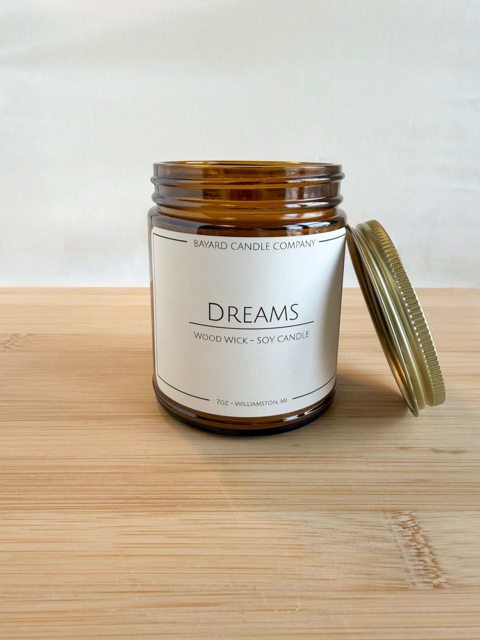 Dreams wood wick soy candle in amber jar with lid off, showing natural soy wax and wood wick