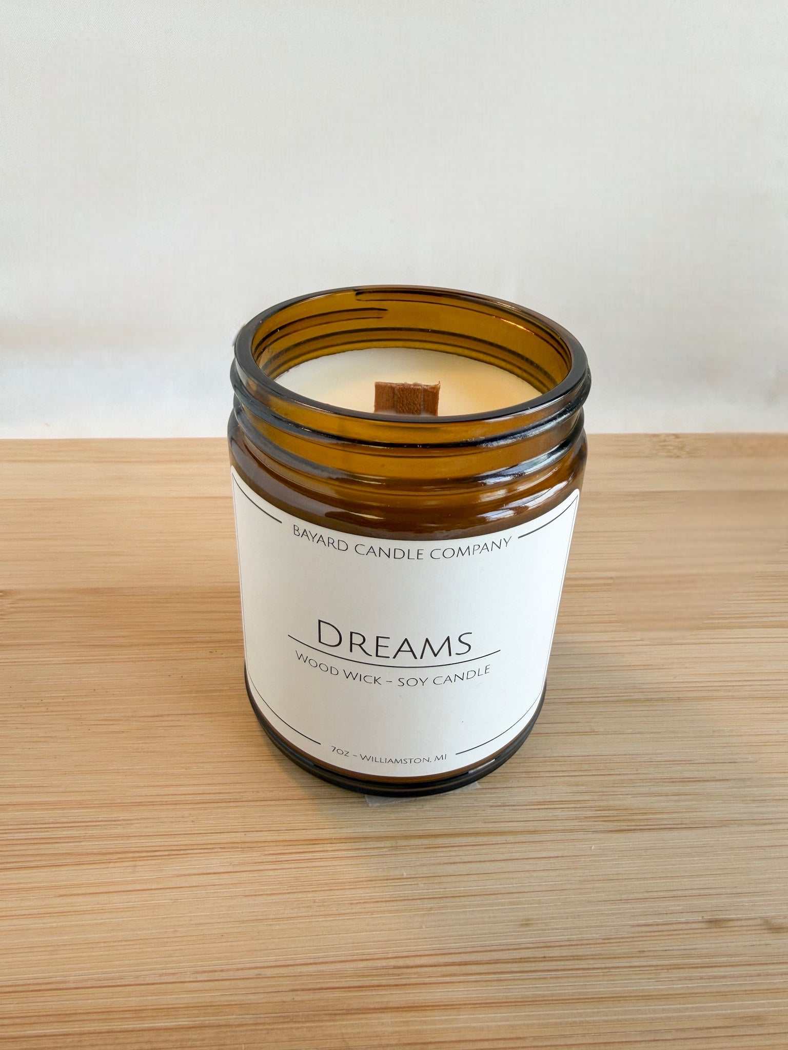 Top view of Dreams wood wick candle showing crackling wood wick and smooth soy wax in amber jar