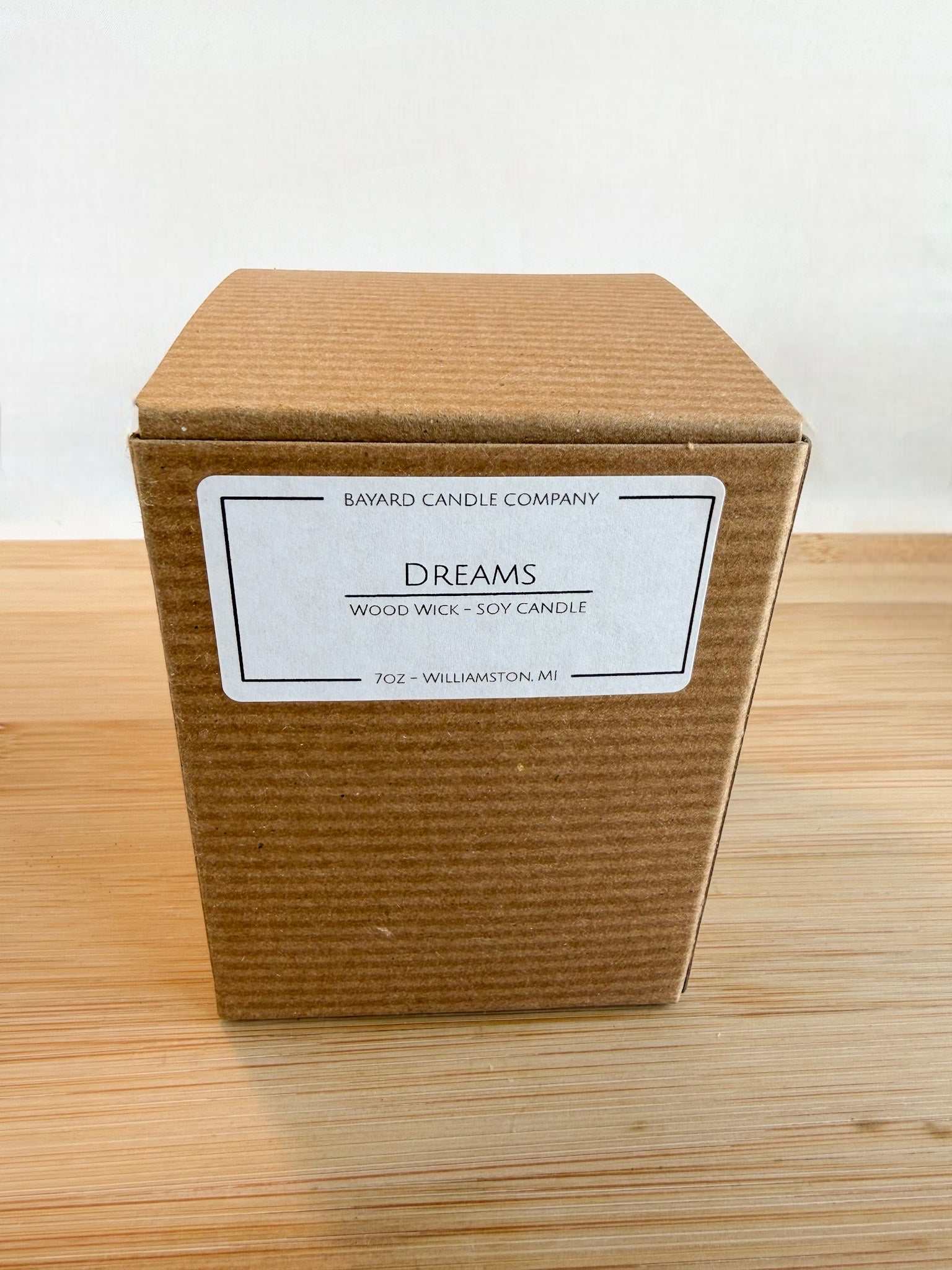 Dreams wood wick candle gift box packaging with labeled kraft box on wood surface