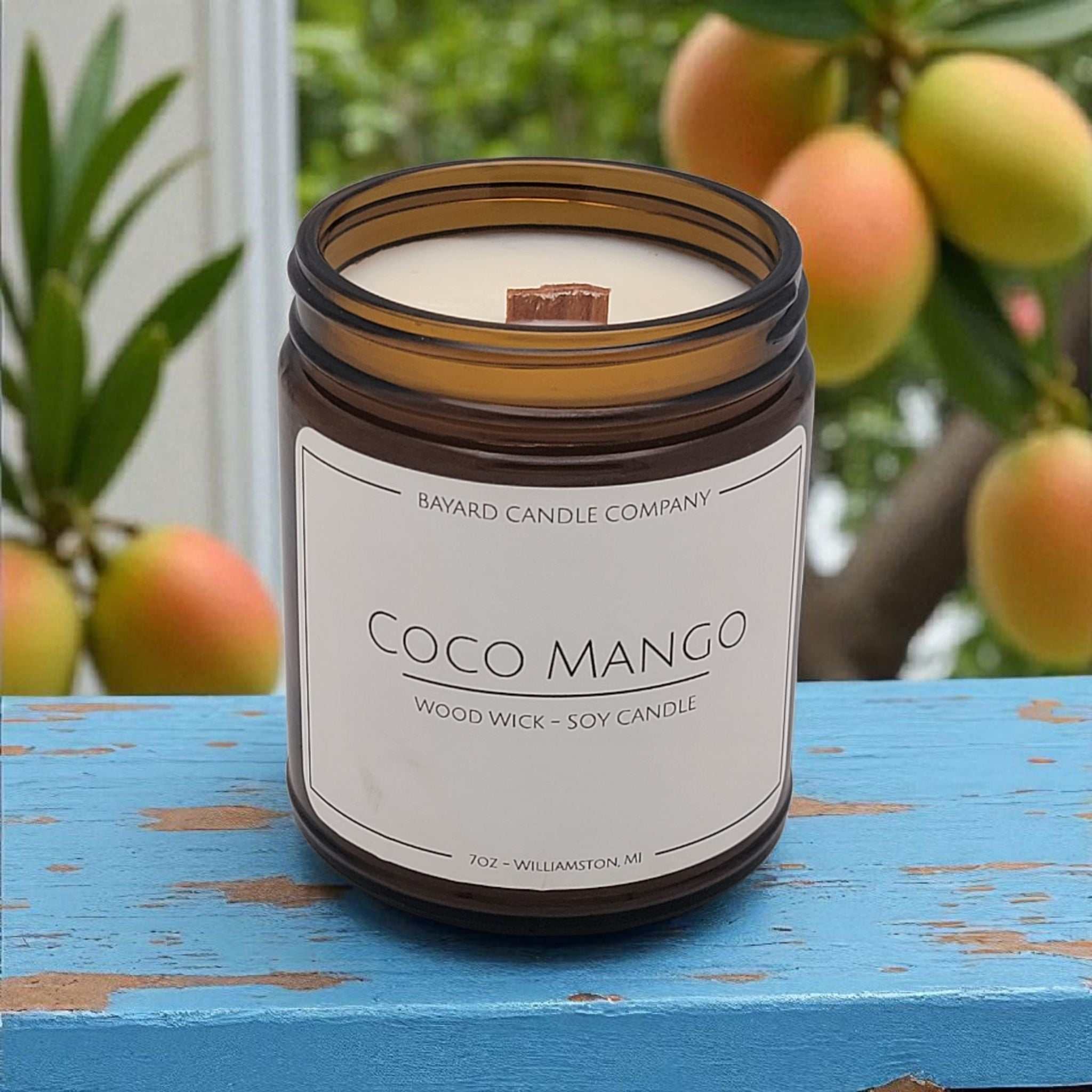 Coco Mango Wood Wick Candle on a blue table.