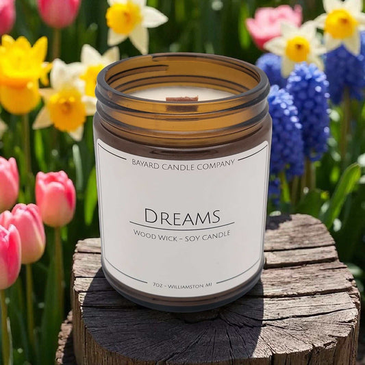 Dreams Wood Wick Candle on a stump by flowers