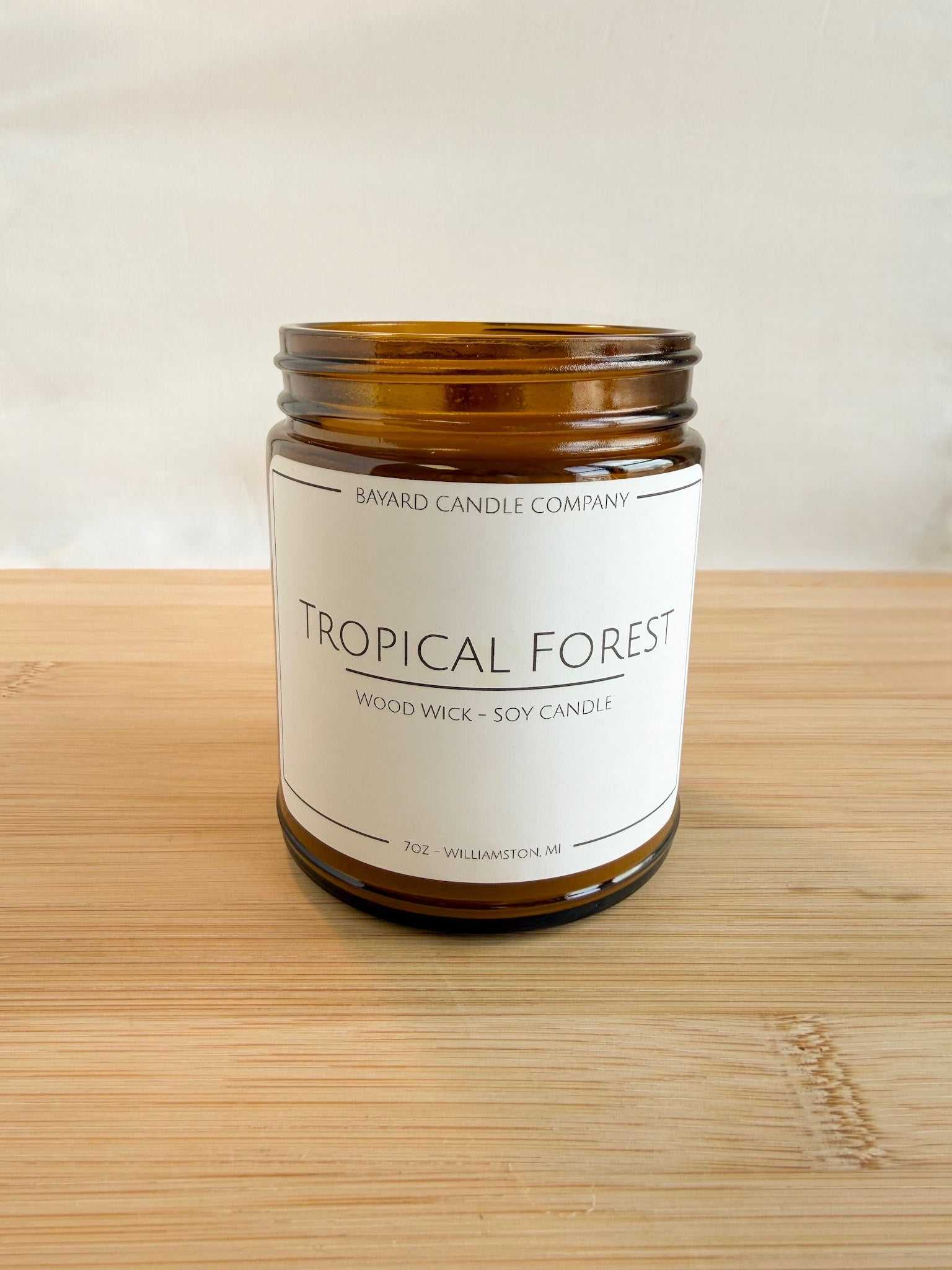 Tropical Forest wood wick soy candle in amber jar with lid off,